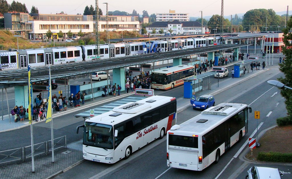 Der Bahnhof in St. Wendel. Im Hintergrund fährt ein Zug und im Vordergrund zwei Busse.