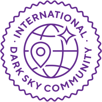 Das Logo der International Dark Sky Community besteht aus einem Planeten in der Mitte mit einem Standortsymbol und einem Stern darauf. Um den Planeten verläuft der Name und darum kräuselt sich ein Kreis.