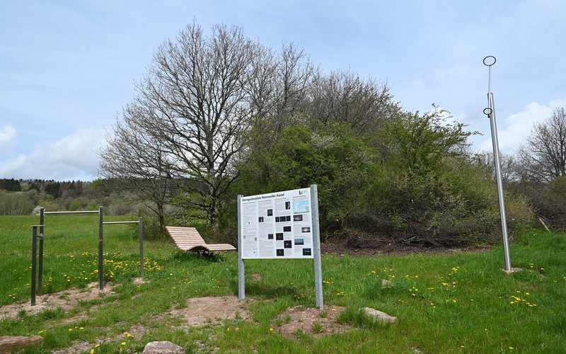 Auf einer grünen Wiese sind eine drehbare Sternkarte mit Infotafel, ein Polarsternfinder mit Peilringen, ein Fernglas- bzw. Teleskopaufsetzer sowie eine dreh- und schwingbare Wellenliege zu finden.