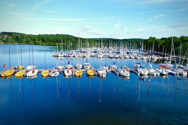 Kreissegelhafen Bostalsee Aus der Vogelperspektive ist der Kreissegelhafen mit unzähligen Segelbooten auf blauem Wasser mit grünen Hügeln im Hintergrund zu sehen.