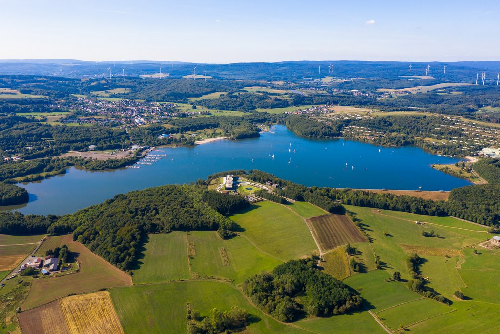 Blick von oben auf den blauen Bostalsee mit Dörfern und Feldern drumherum