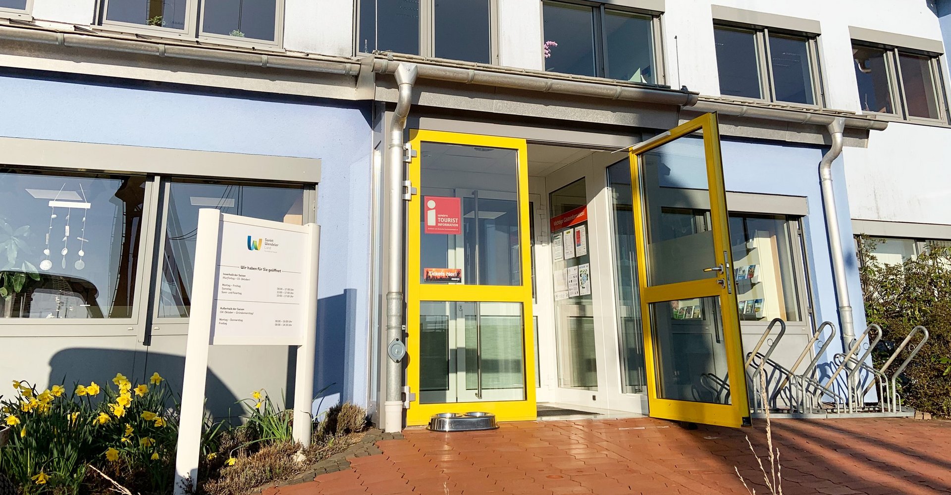Ein blaues Gebäude mit einer gelben Tür, die geöffnet ist.