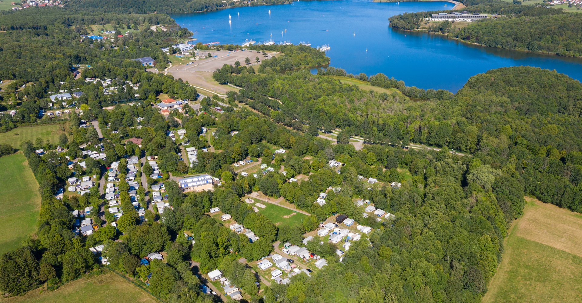 Die verschiedenen Buchten und Gebäude des Campingplatzes mit dem Bostalsee im Hintergrund.