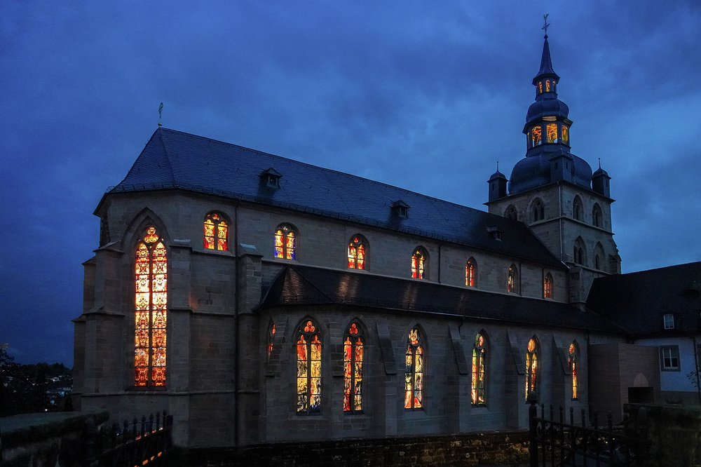 Im alleinigen Fokus des Bildes befindet sich die Benediktinierabtei Tholey bei Nacht. Aus den Fenstern der Abtei scheint helles Licht.
