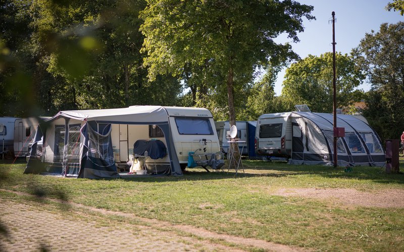 2 Wohnwagen stehen auf dem Campingplatz Bostalsee im Grünen.