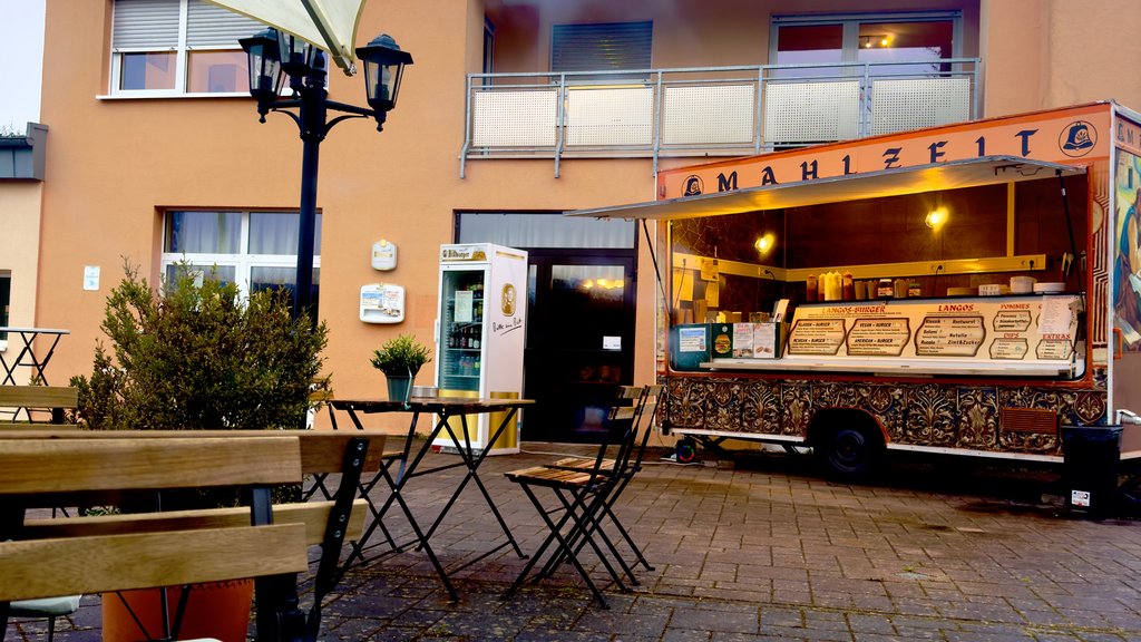 Ein Foodtruck steht vor einem Gebäude. Davor sind Sitzgarnituren aufgebaut, auf denen Gäste ihr Essen genießen können.