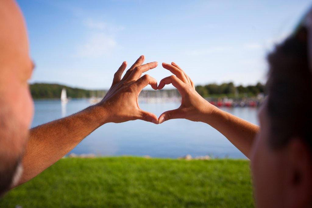 Ein Mann und eine Frau halten ihre Finger so zusammen, dass sie ein Herz ergeben.