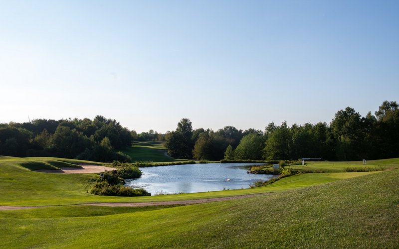 Der grüne Golfplatz des Wendelinus Golfparks mit einem Wasserhindernis.