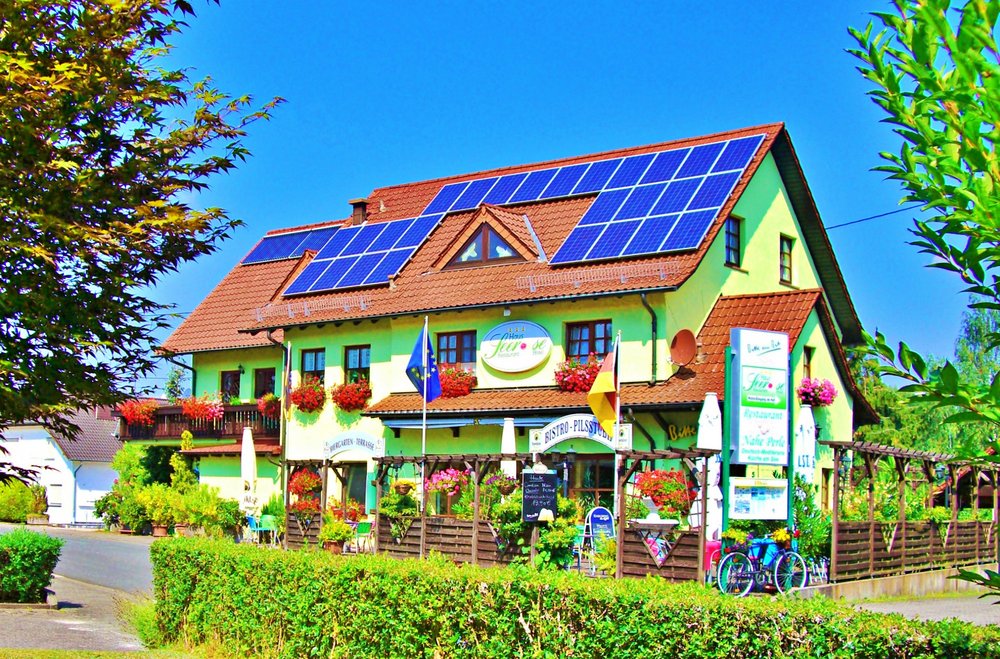 Außenansicht Seerose Hotel Garni Das Haus Seerose Hotel Garni ist ein buntes Haus im Landhausstil mit vielen bunten Blumen an den Fenstern und ums Haus inklusive Terrasse zum Verweilen.