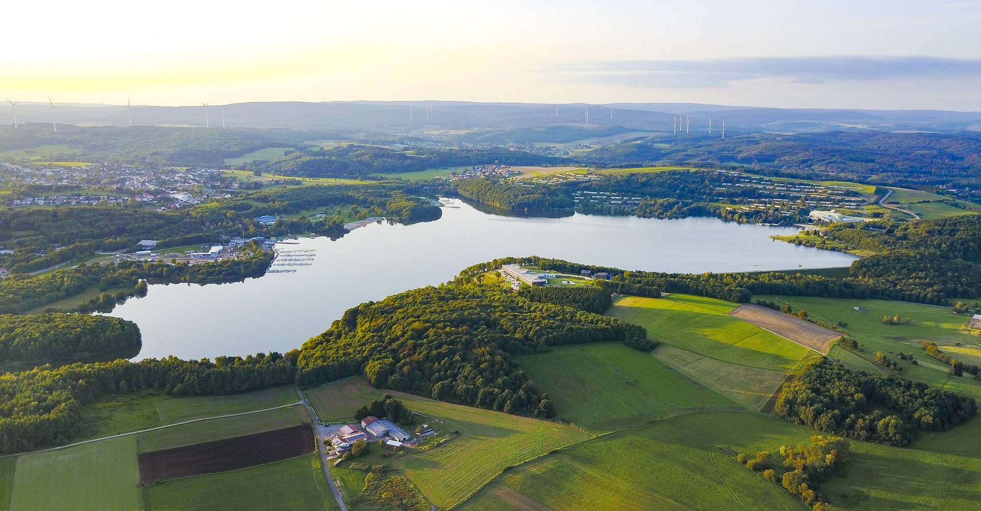Der Bostalsee von oben. Er ist umgeben von zwei Dörfern, ganz vielen Feldern und Wald.
