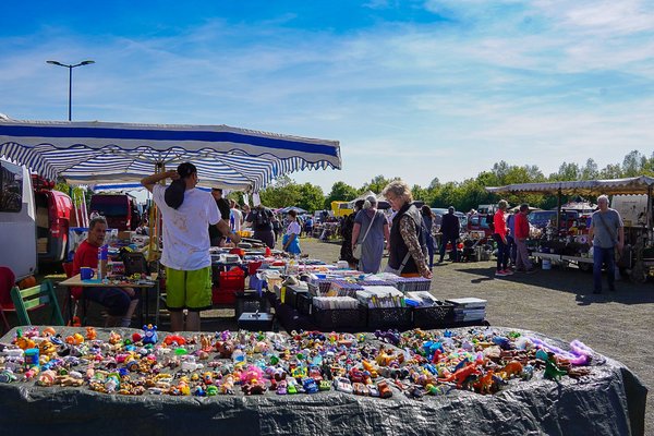 Viele Verkaufsstände stehen auf einer großen Outdoor-Veranstaltungsfläche. Menschen schauen sich die ausgestellten Waren an.