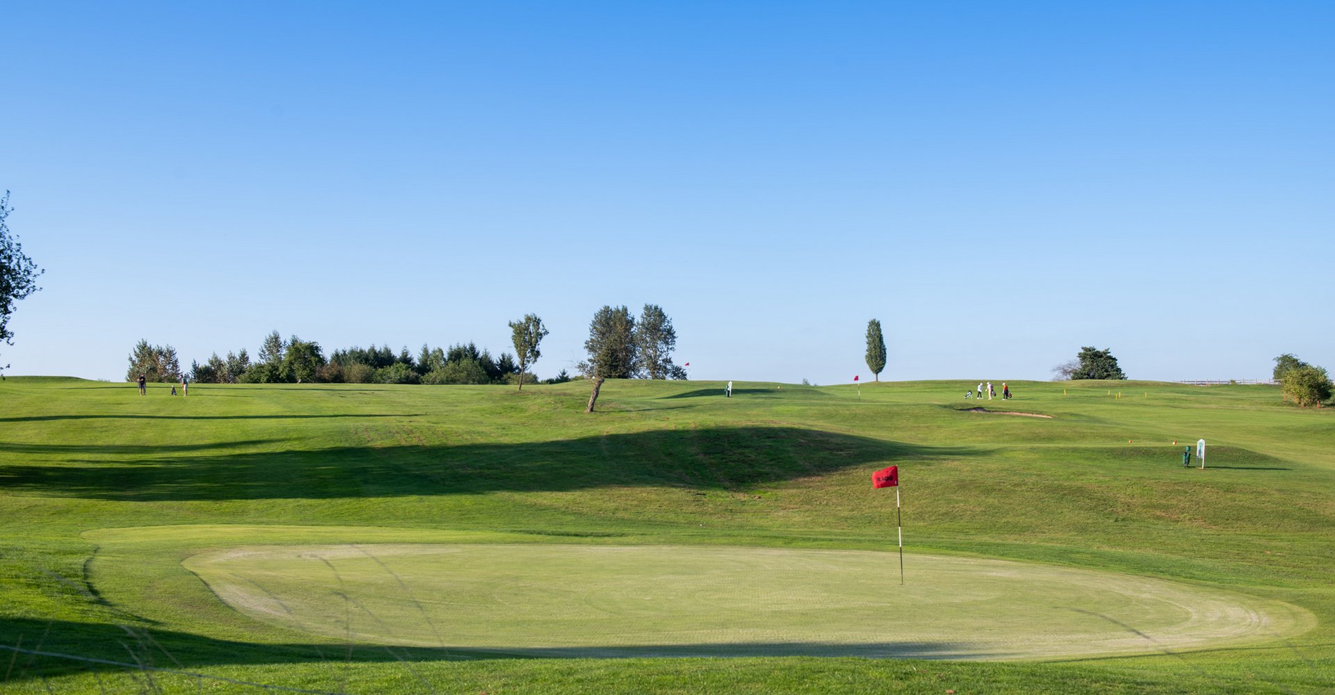 Blick auf den grünen Platz des Wendelinus Golfparks mit seinen Löchern.