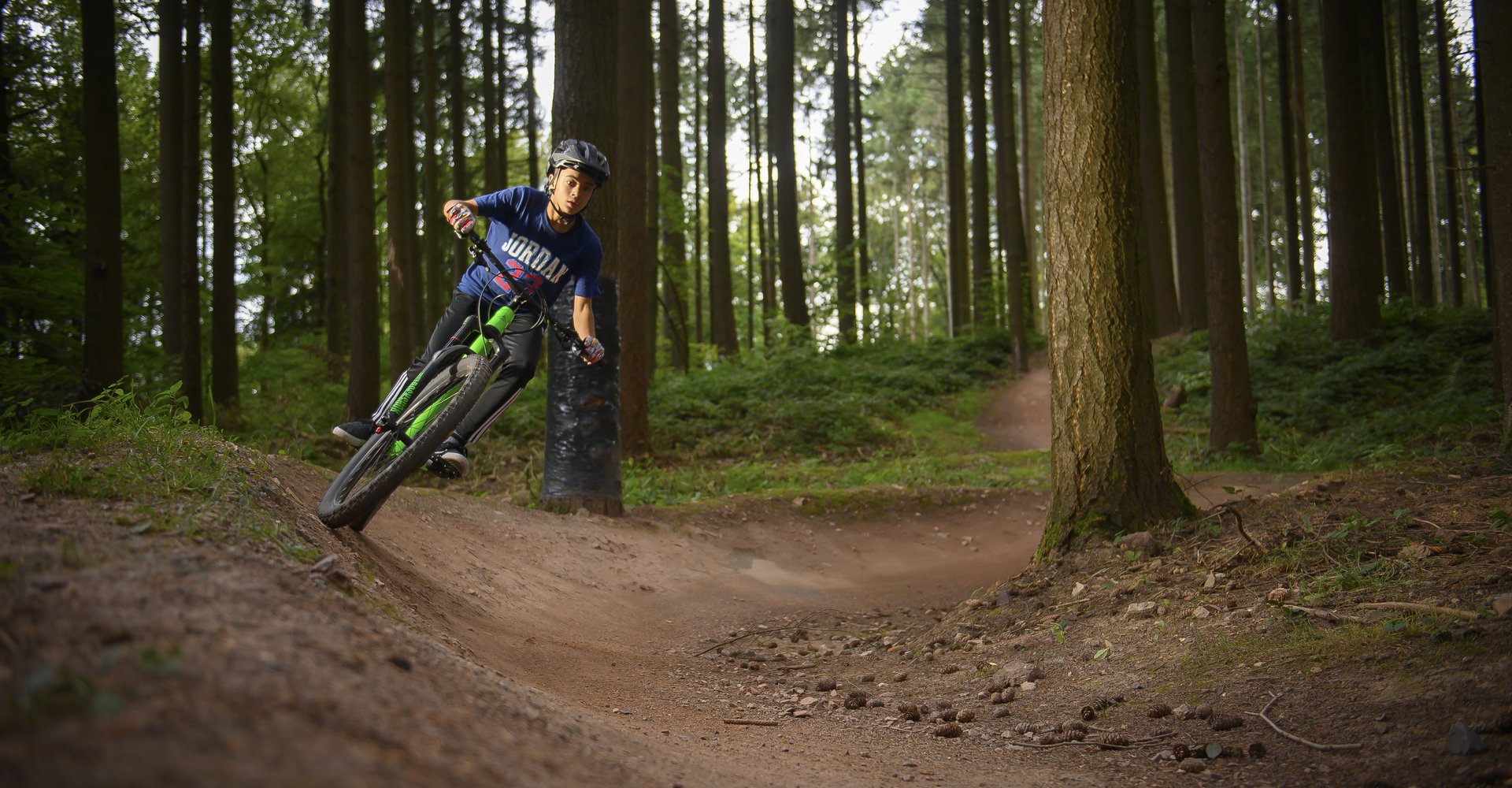 Ein junger Mann fährt mit seinem Mountainbike auf extra angelegten Pfaden durch den Wald.