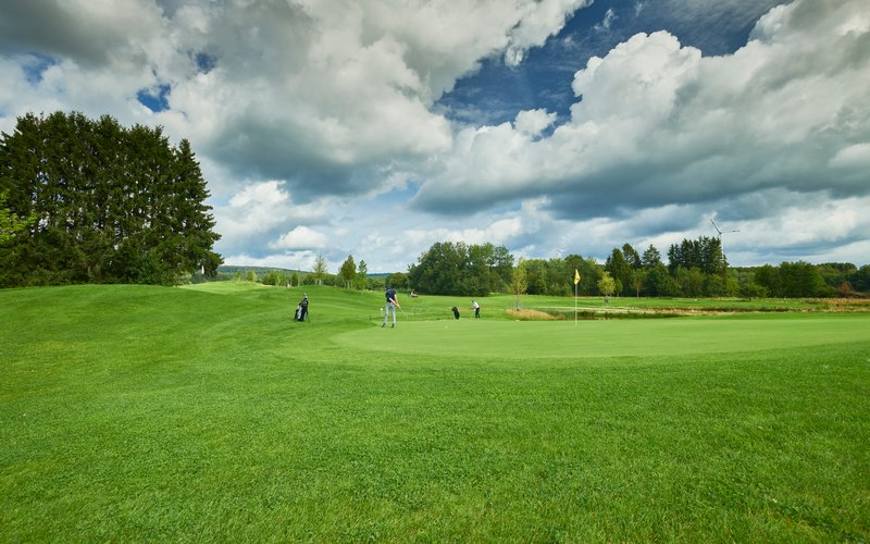Blick auf den grünen Golfplatz mit seinen Löchern.