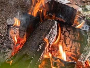 Grillfeuer Mietwohnwagen Vor einem Mietwohnwagen des Campingplatzes Bostalsee hat es sich ein Pärchen mit einem Getränk am Grillfeuer, über dem ein Schwenker hängt, gemütlich gemacht.