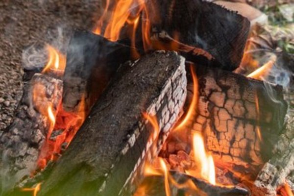 Grillfeuer Mietwohnwagen Vor einem Mietwohnwagen des Campingplatzes Bostalsee hat es sich ein Pärchen mit einem Getränk am Grillfeuer, über dem ein Schwenker hängt, gemütlich gemacht.